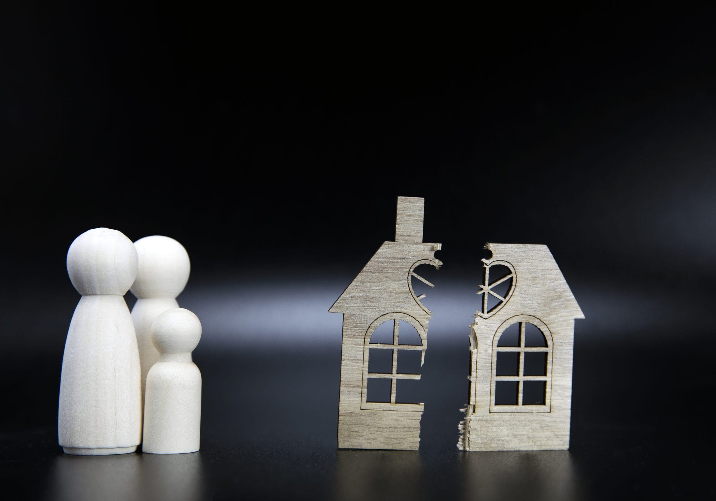 Divorce, division of property, poverty and no money concept. Wooden broken house on black background. Mortgage, rent, realtor concept copy space space for text